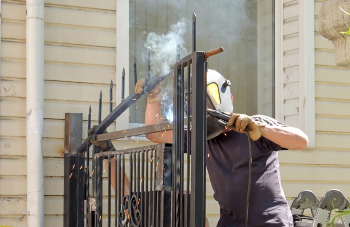 A technician performs welding on a wrought iron gate during unexpected gates repairs at a Houston residential property.