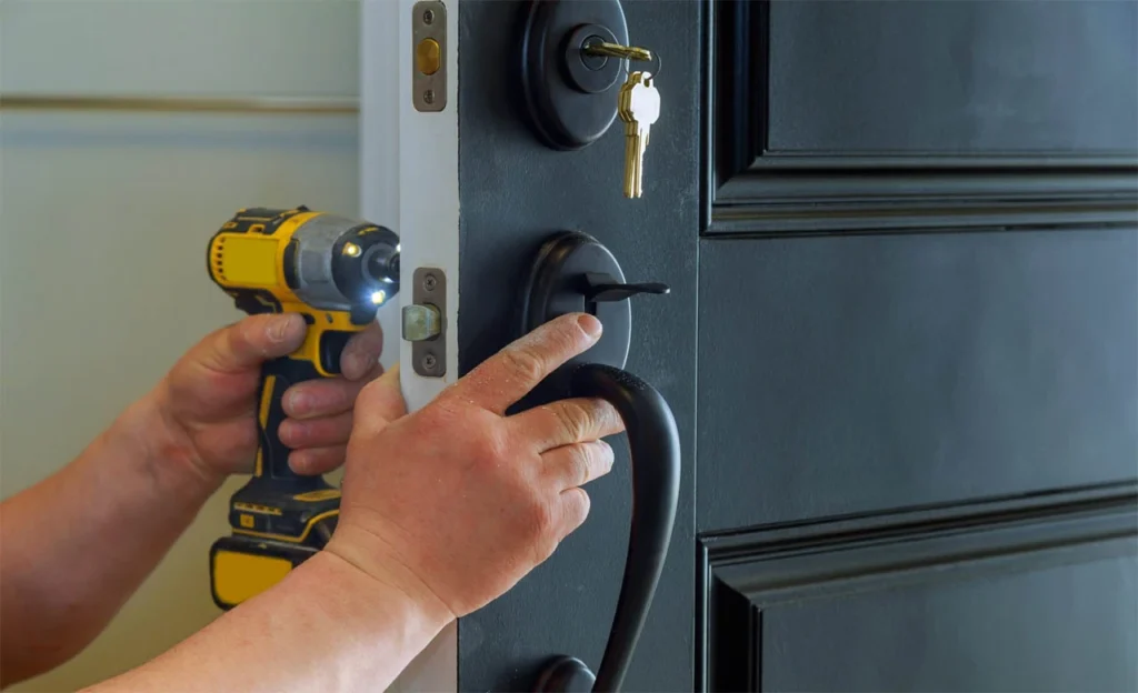 A locksmith tightens a deadbolt lock with a power drill as part of unexpected gates repairs following a gate failure affecting home entry.